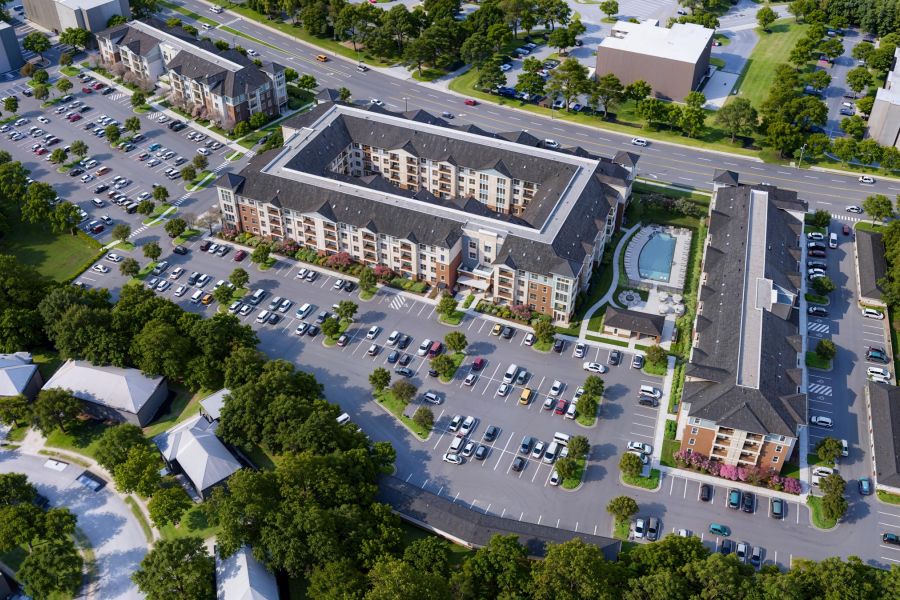 Attain at Greenbrier apartment homes with Aerial view of an apartment complex with large parking lots, a pool, trees, and nearby roads.